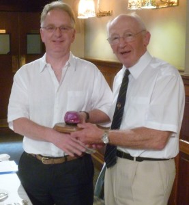 Secretary Craig Wilson receives Rotarian of the Year award from outgoing President Neil Beattie.